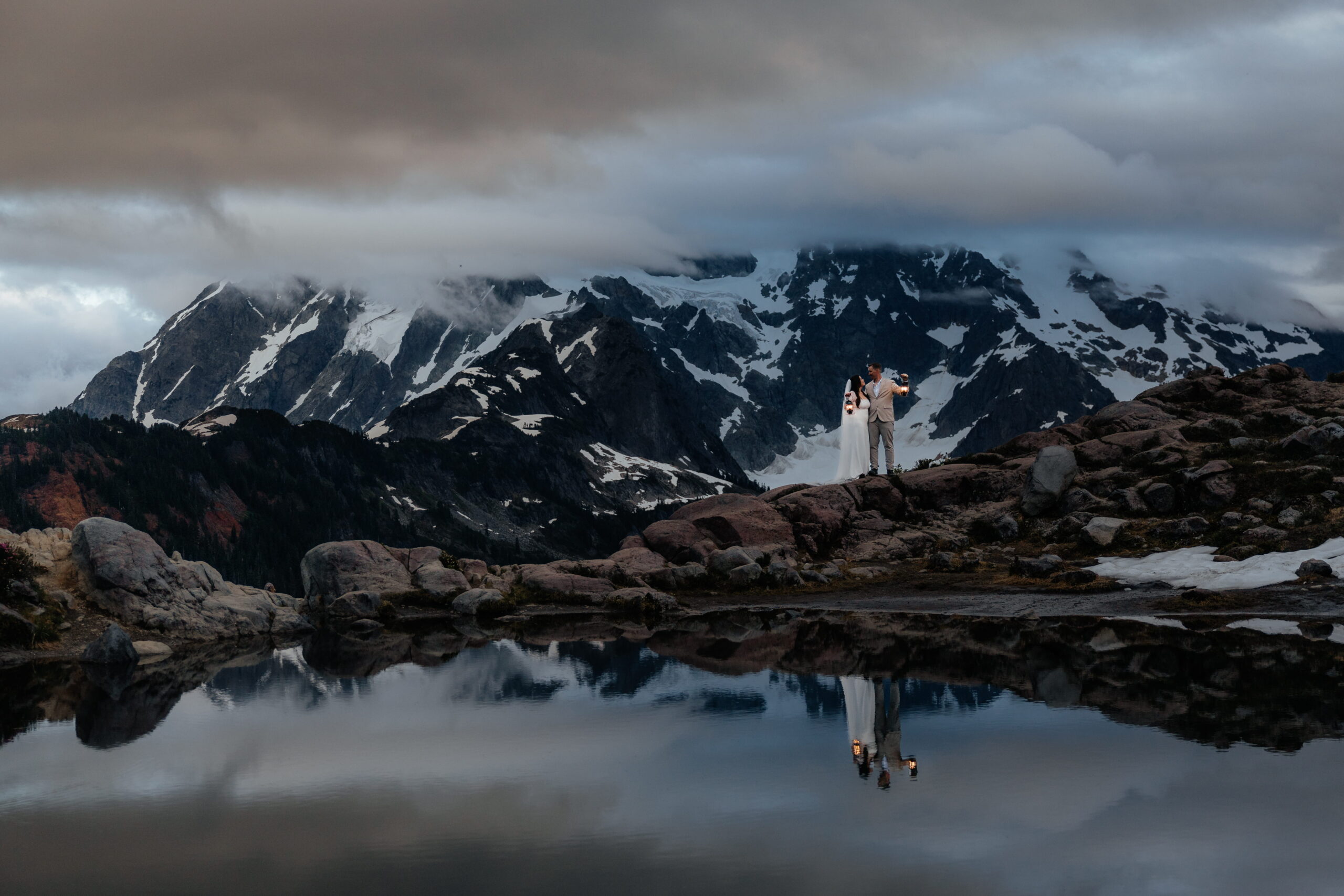 Couples holds lanterns on a mountain trail by a reflection pond at Artist Point. 