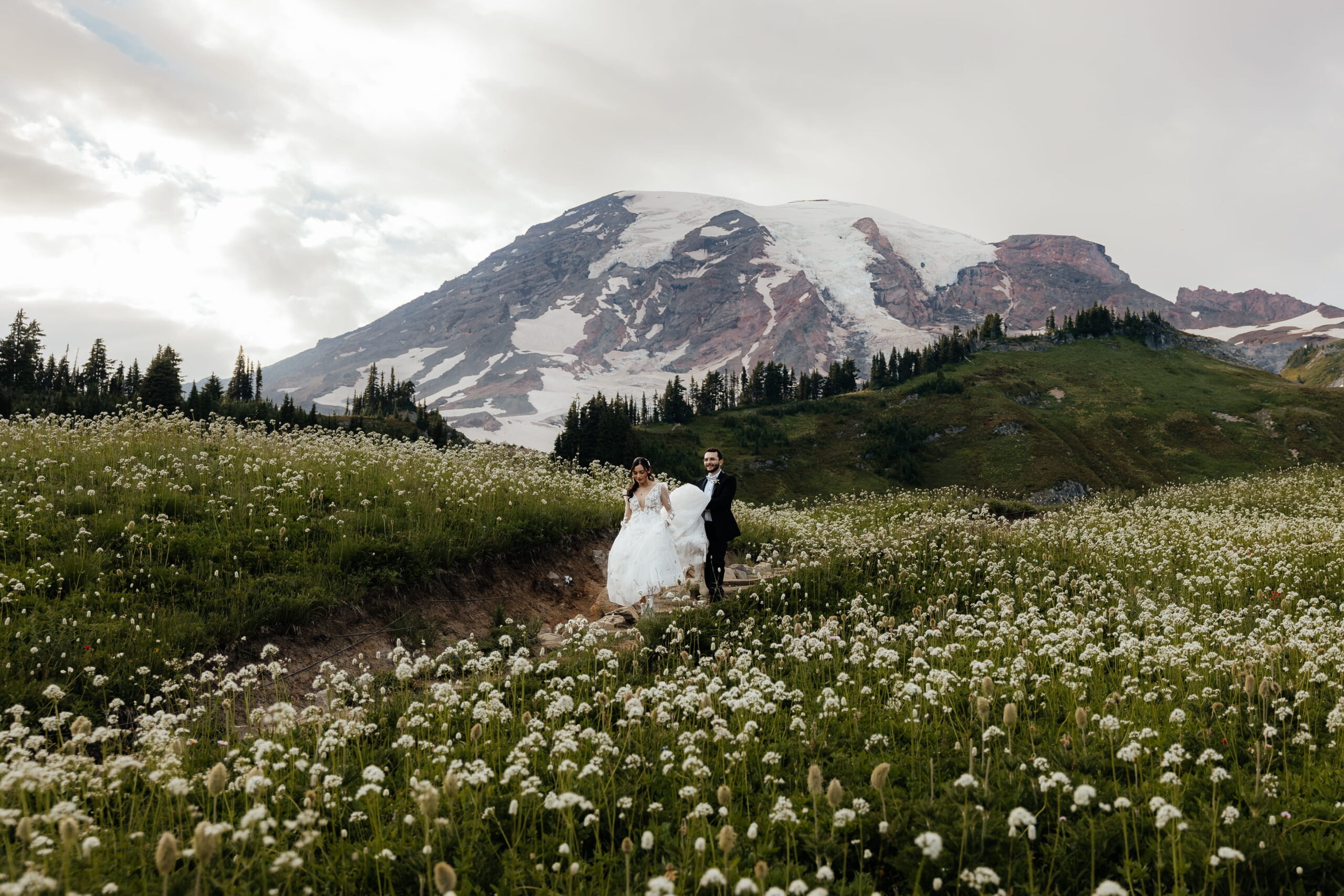 Couples hikes a wildflower trail in front of Mt Rainier during their elopement in Washington.