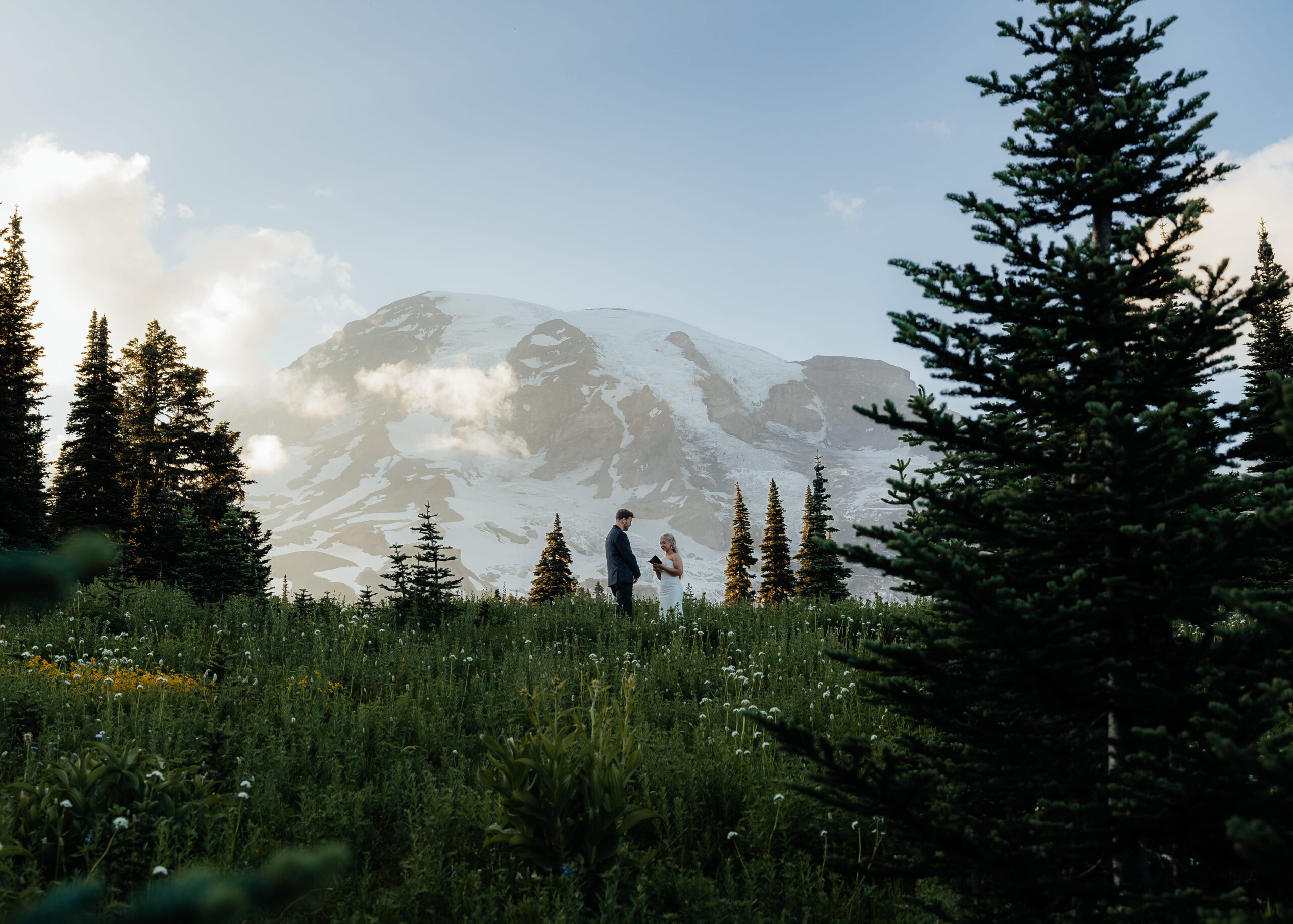 Newlyweds exchange vows in a field in front of Mt Rainier during their elopement at Skyline Trail, one of the best places to elope in Washington state.