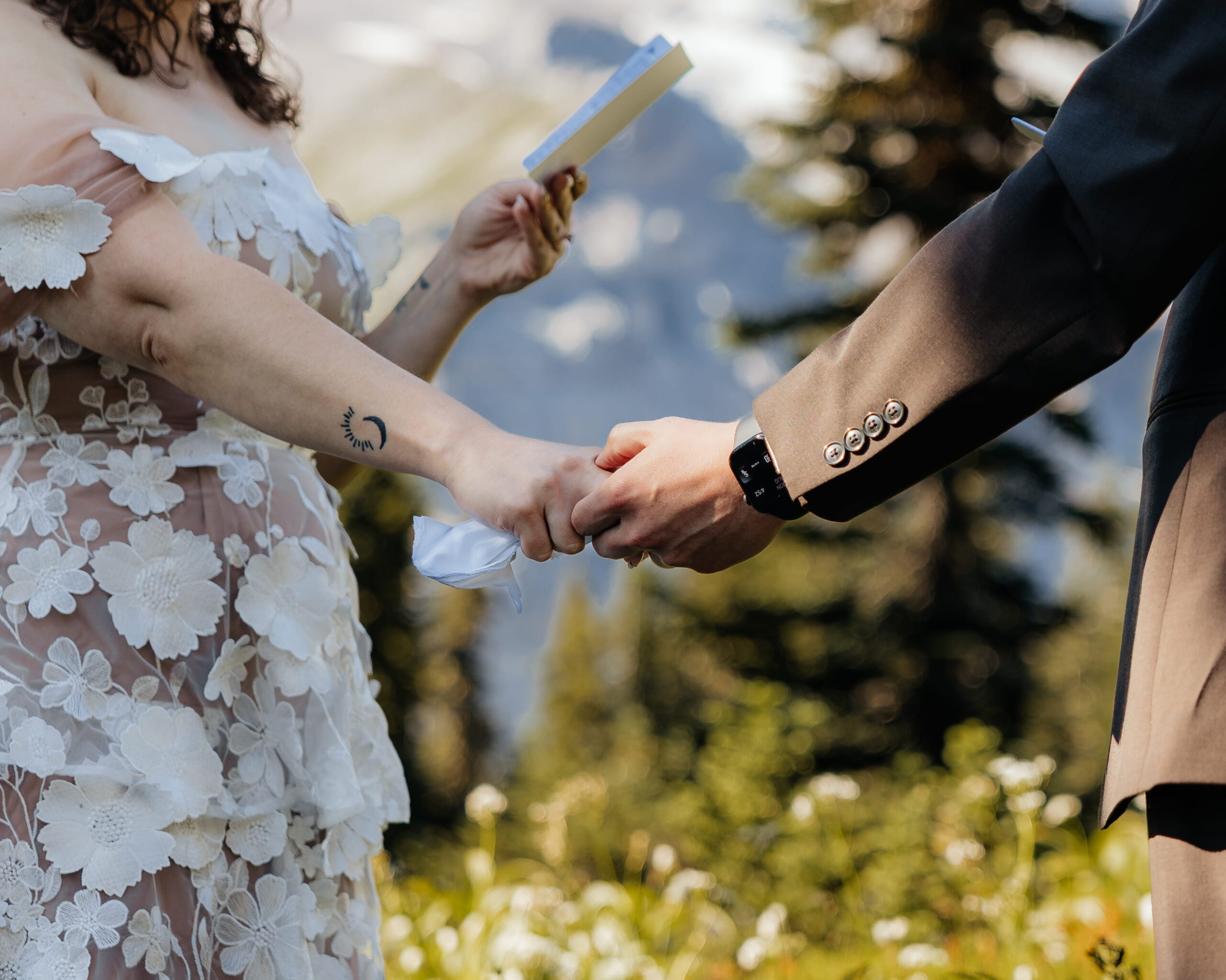 Newlyweds hold hands while reading vows at their Mt Rainier elopement ceremony.