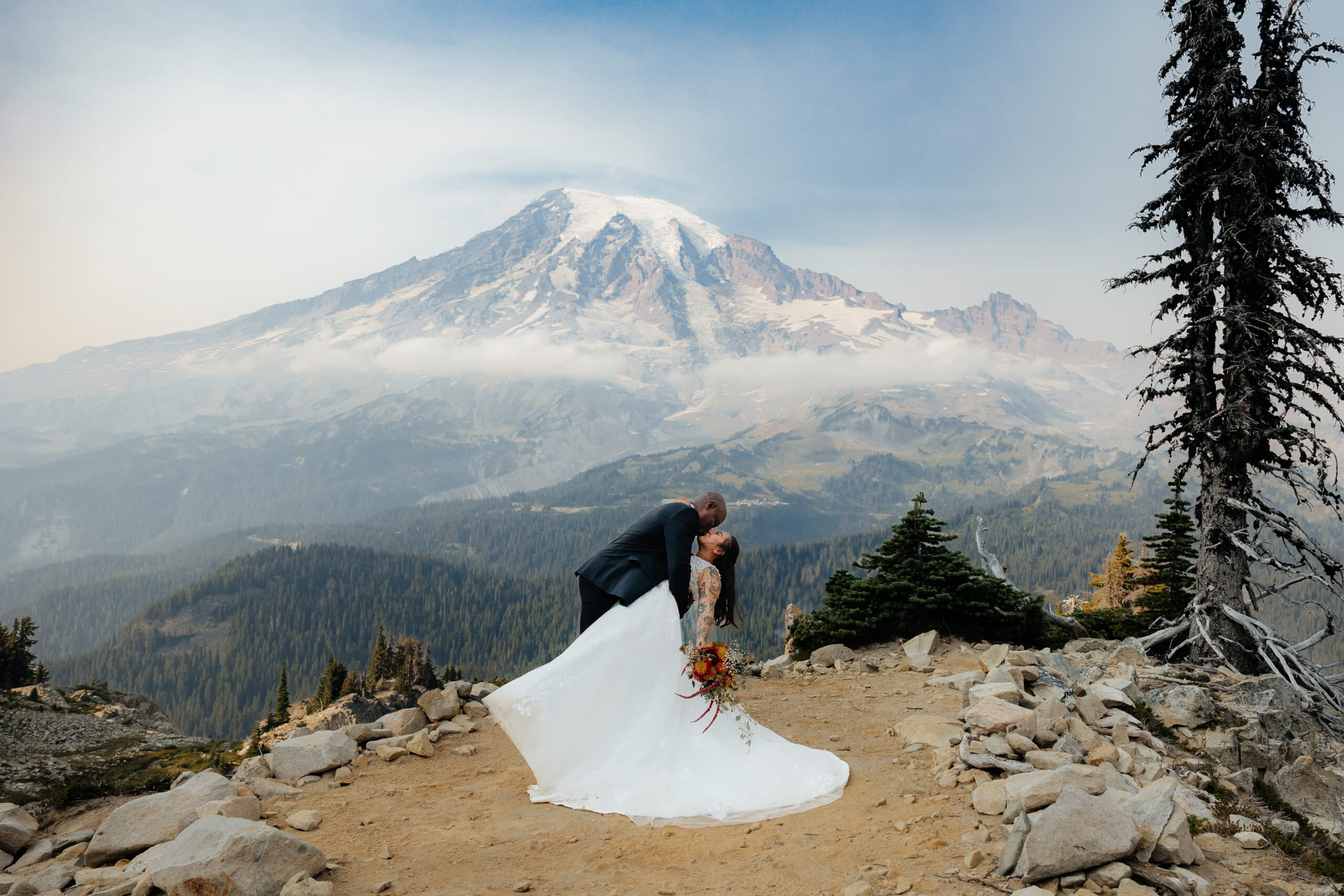Groom dips bride for a kiss at their Mt Rainier wedding ceremony.