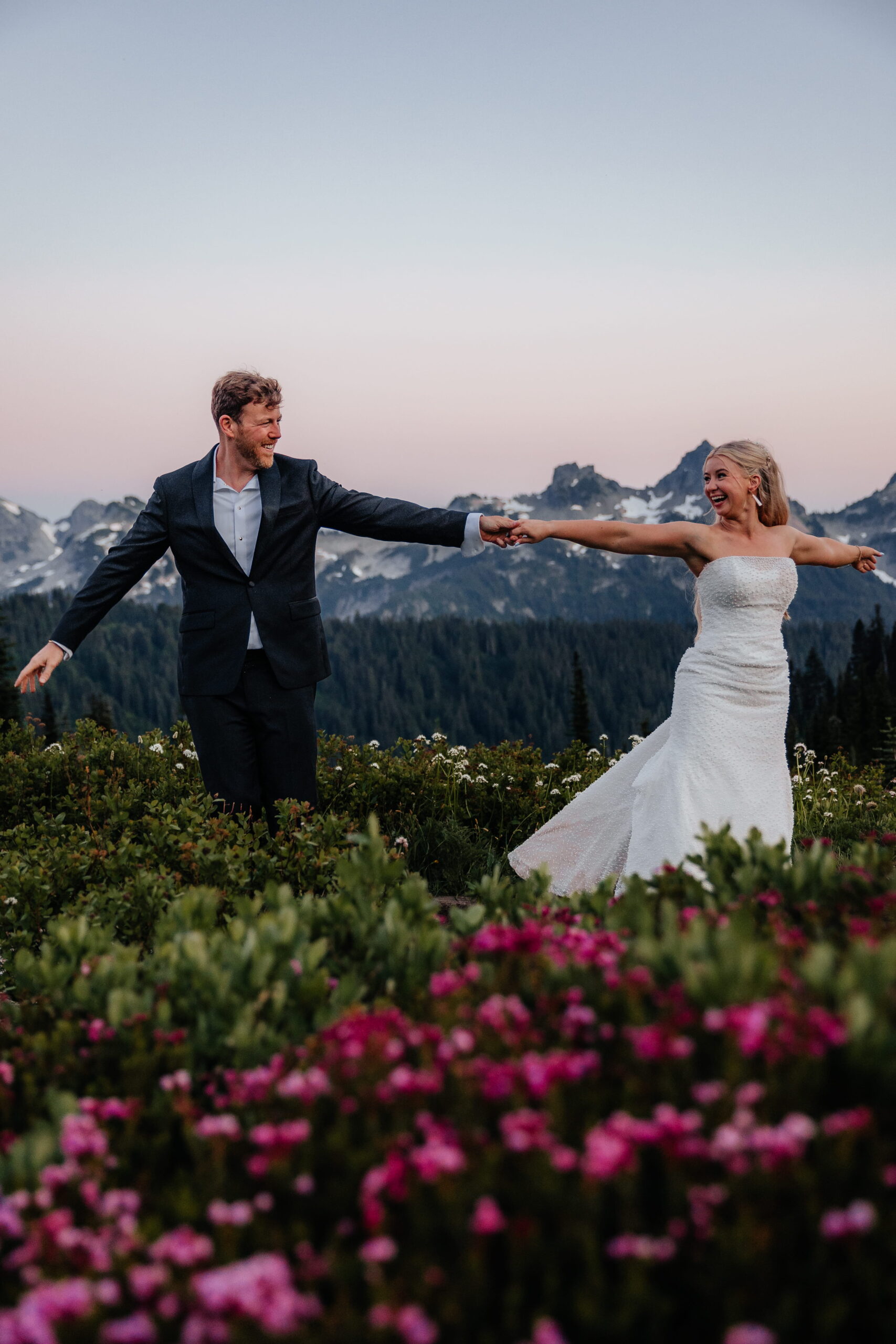 Newlyweds dance in a field of wildflowers during their elopement at Paradise Mt Rainier. 