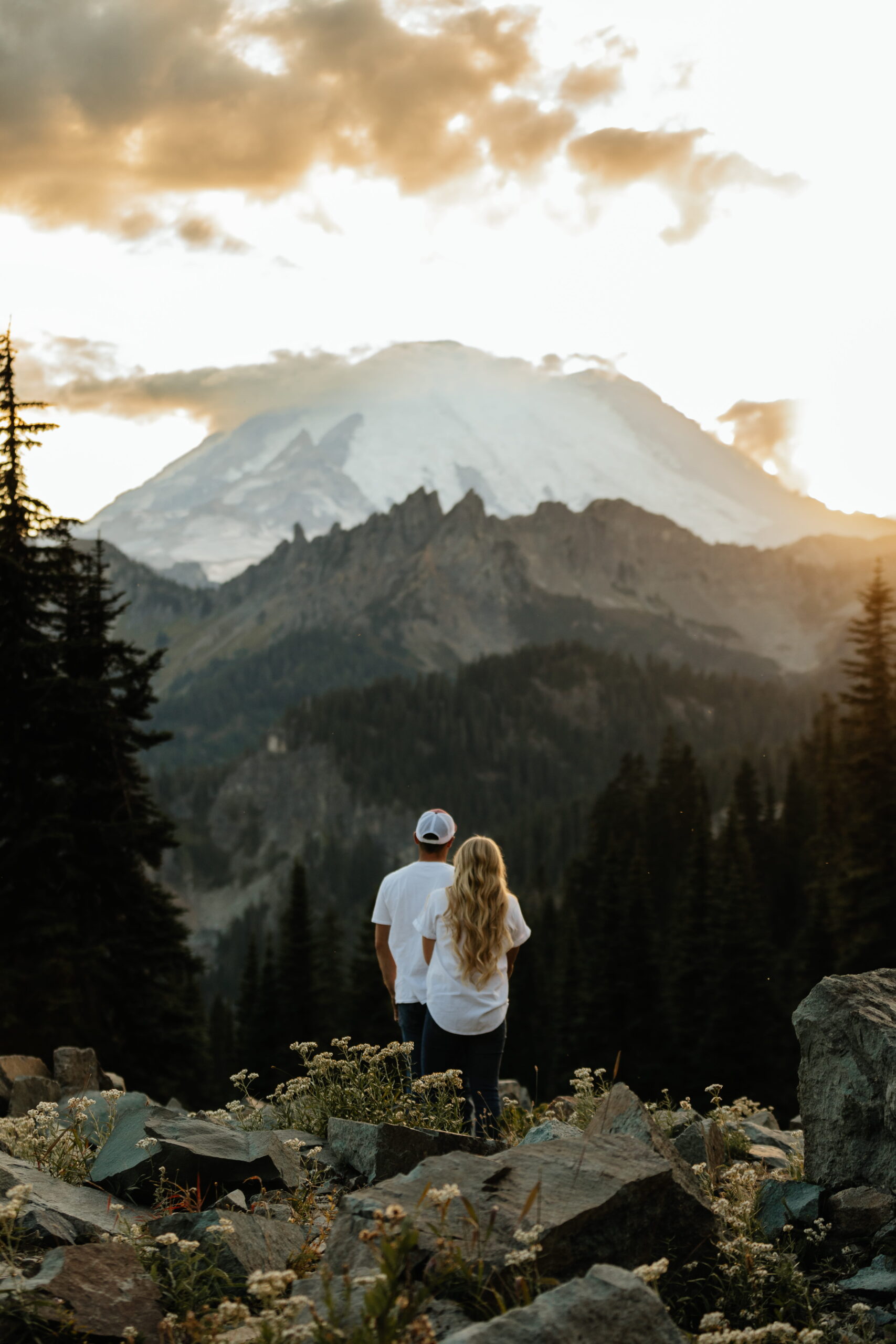 Couple walks out across a mountain trail to view Mt Rainier. 