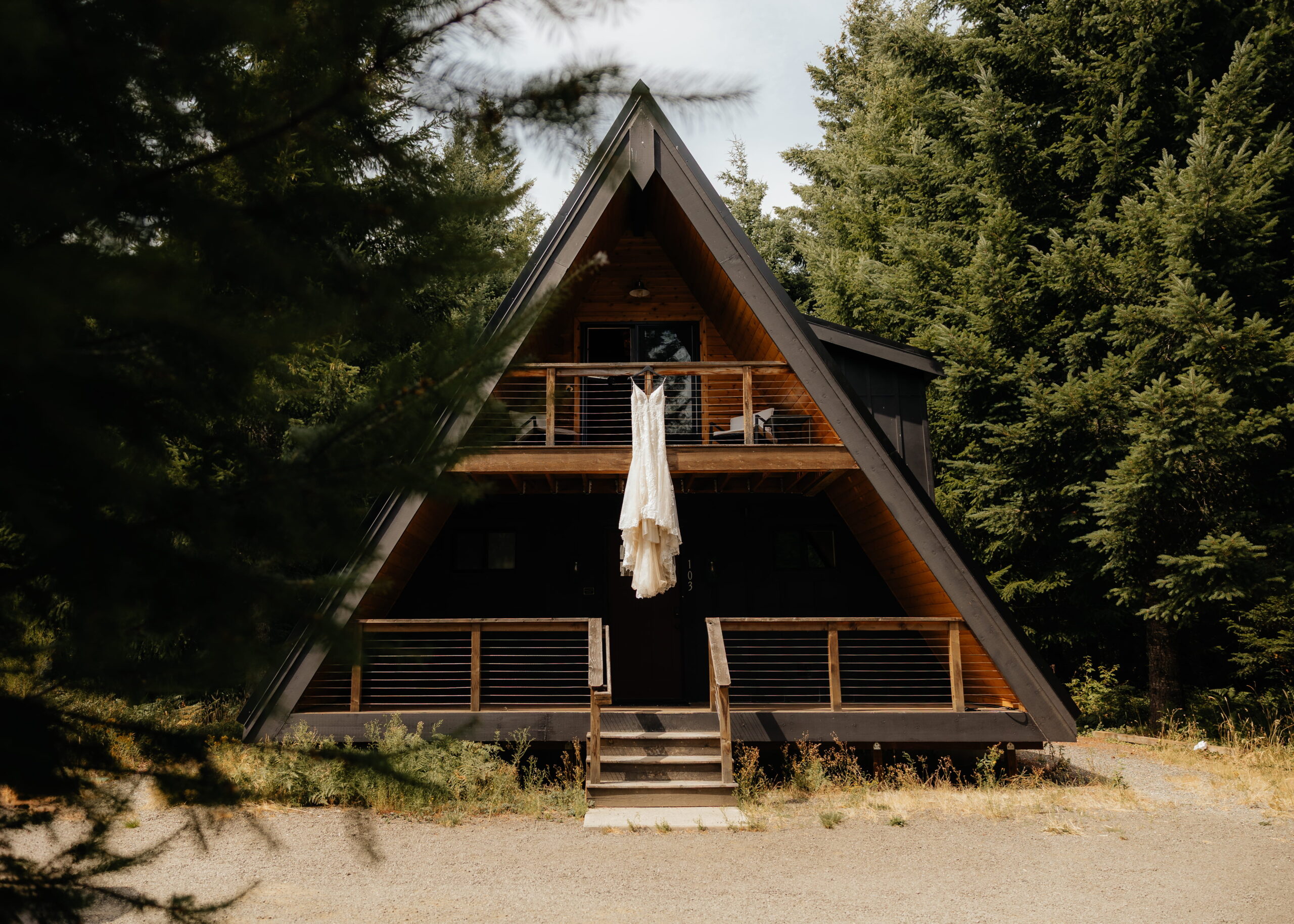 White wedding dress hangs from the balcony of a Mt Rainier a-frame elopement cabin.