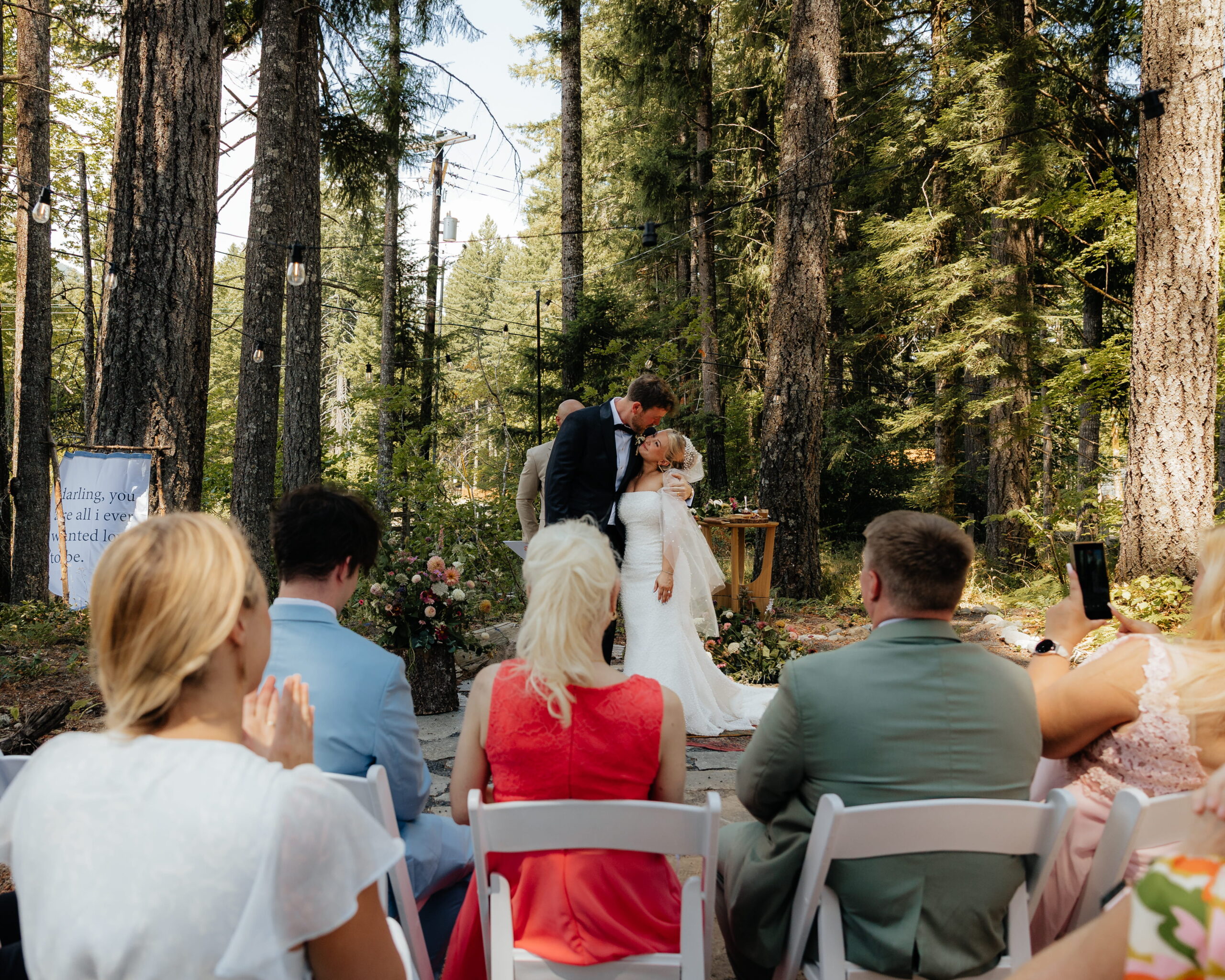 Newlyweds kiss during their forest wedding ceremony at their A-frame cabin in Washington.