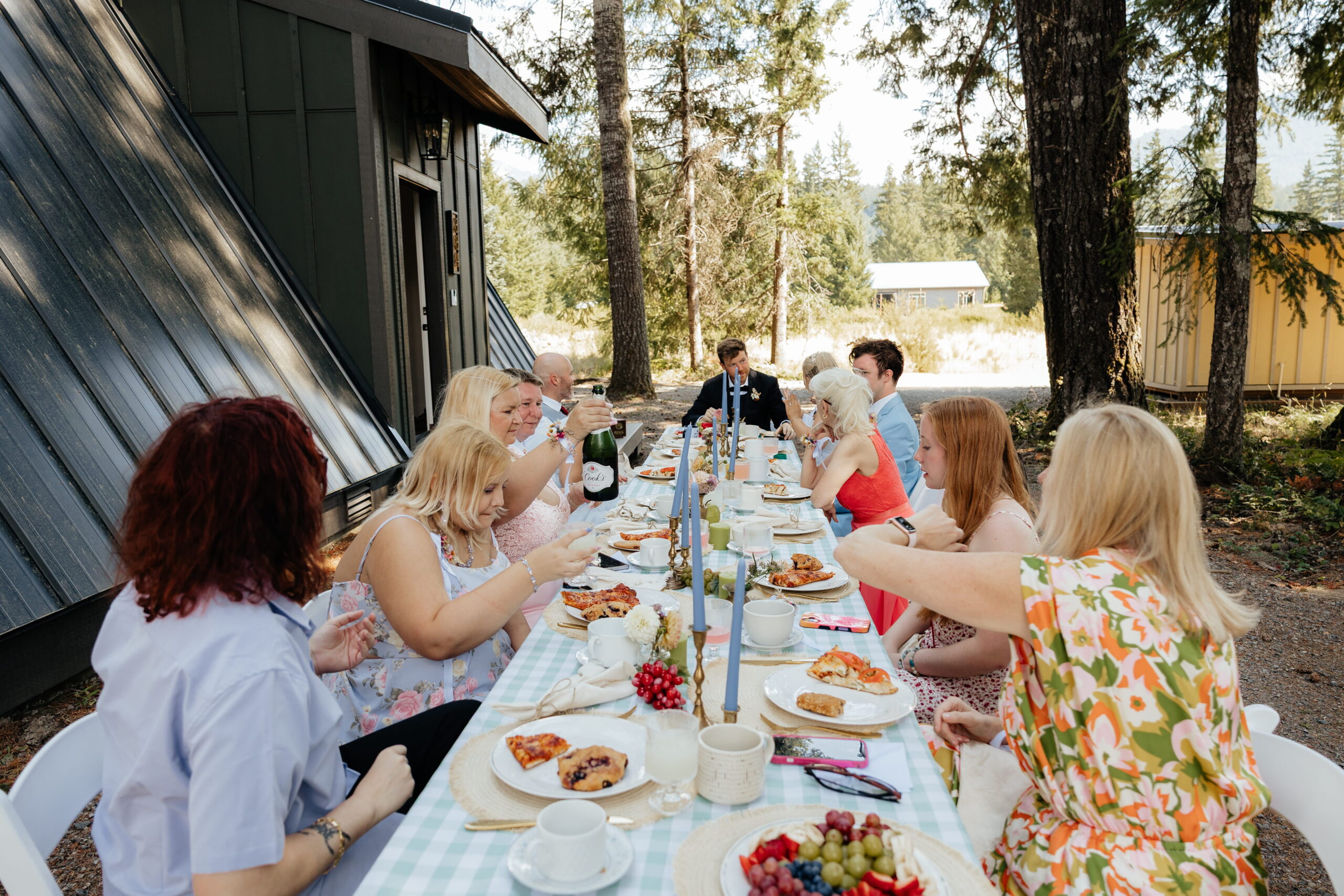 Guests talk and mingle during an outdoor forest microwedding reception at an A-frame cabin in Washington.