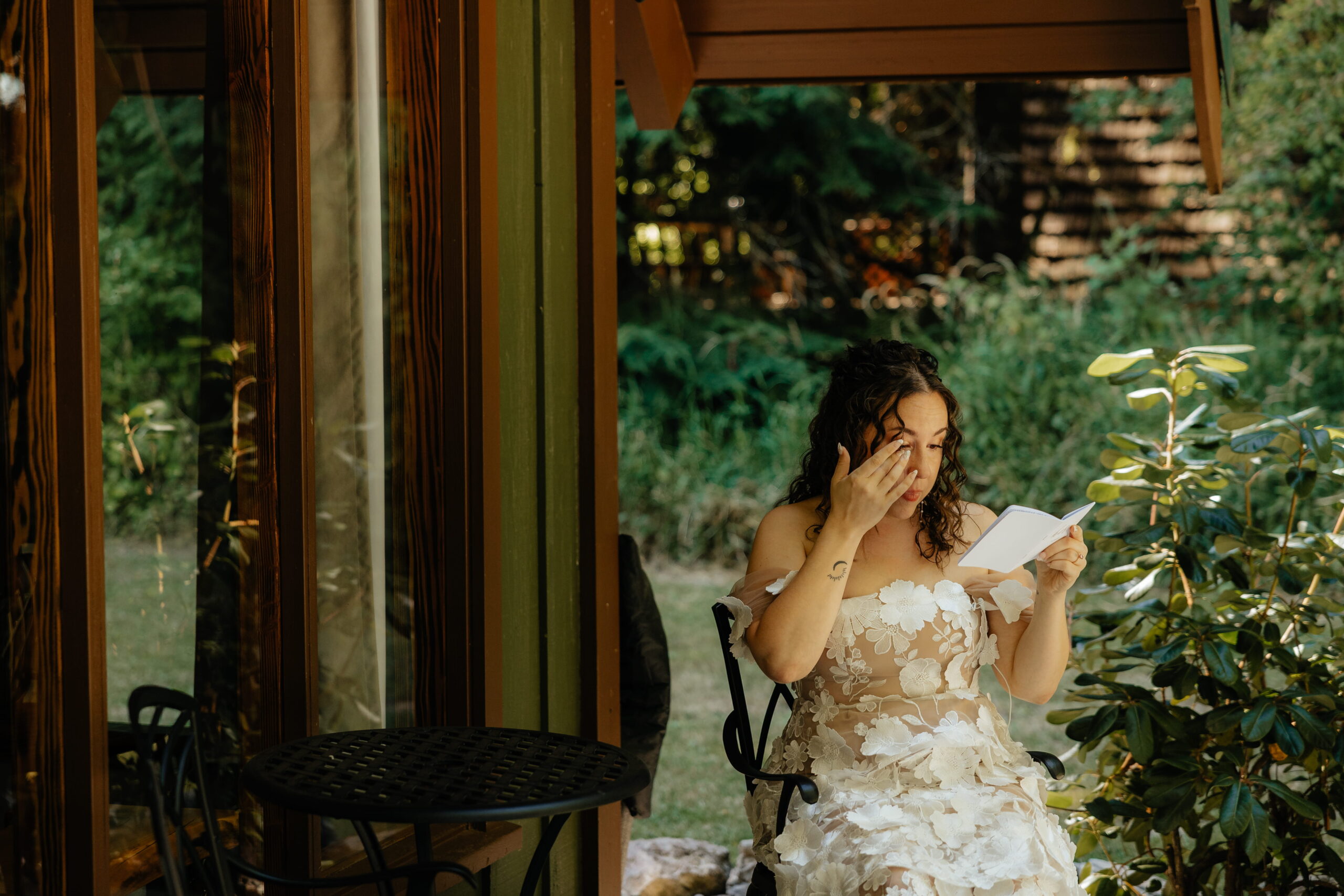 Bride wipes tears while reading a letter at her A-frame elopement cabin near Mt Rainier National Park.