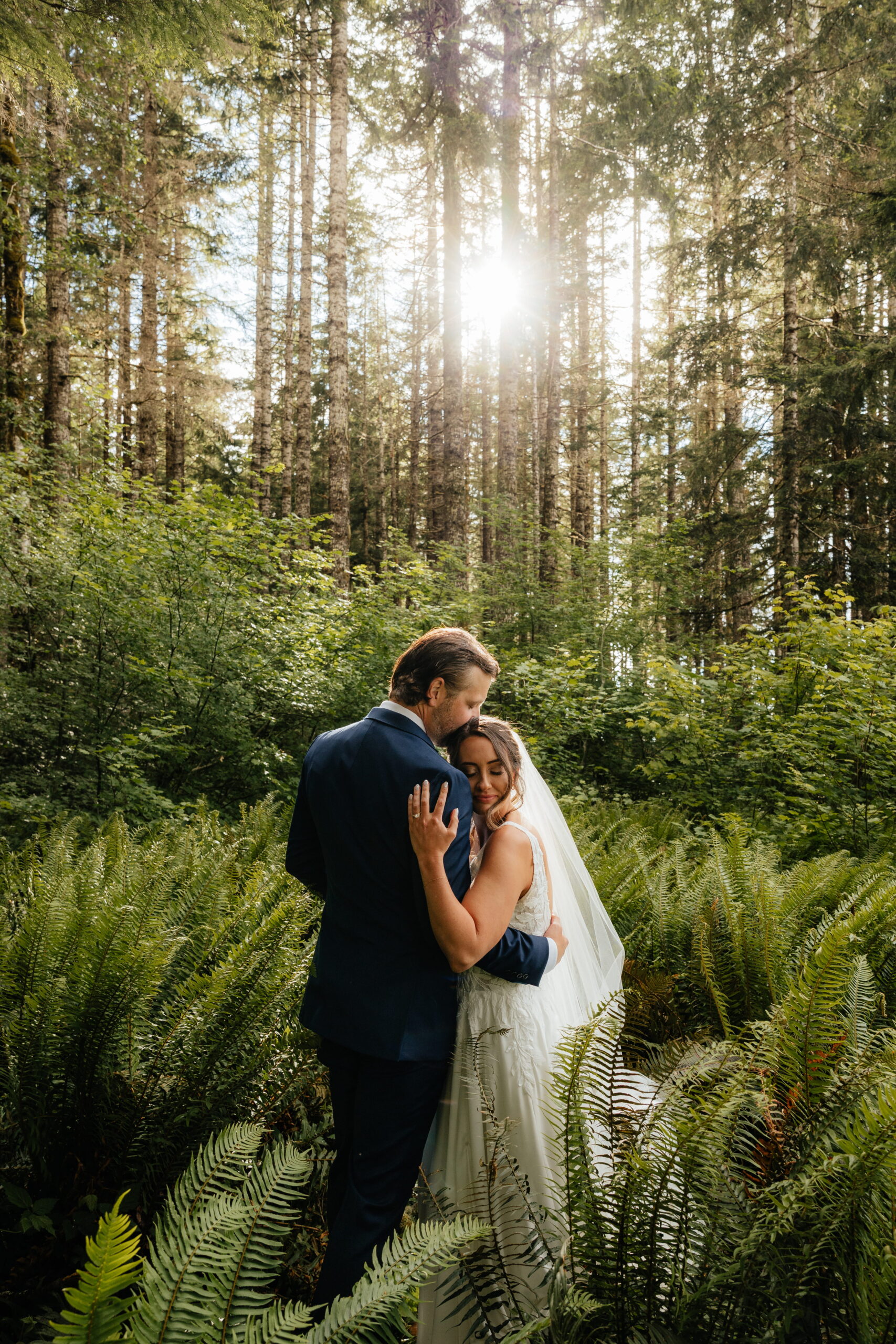 Newlyweds hug in a lush forest during their elopement at Mt. Rainier National Park.