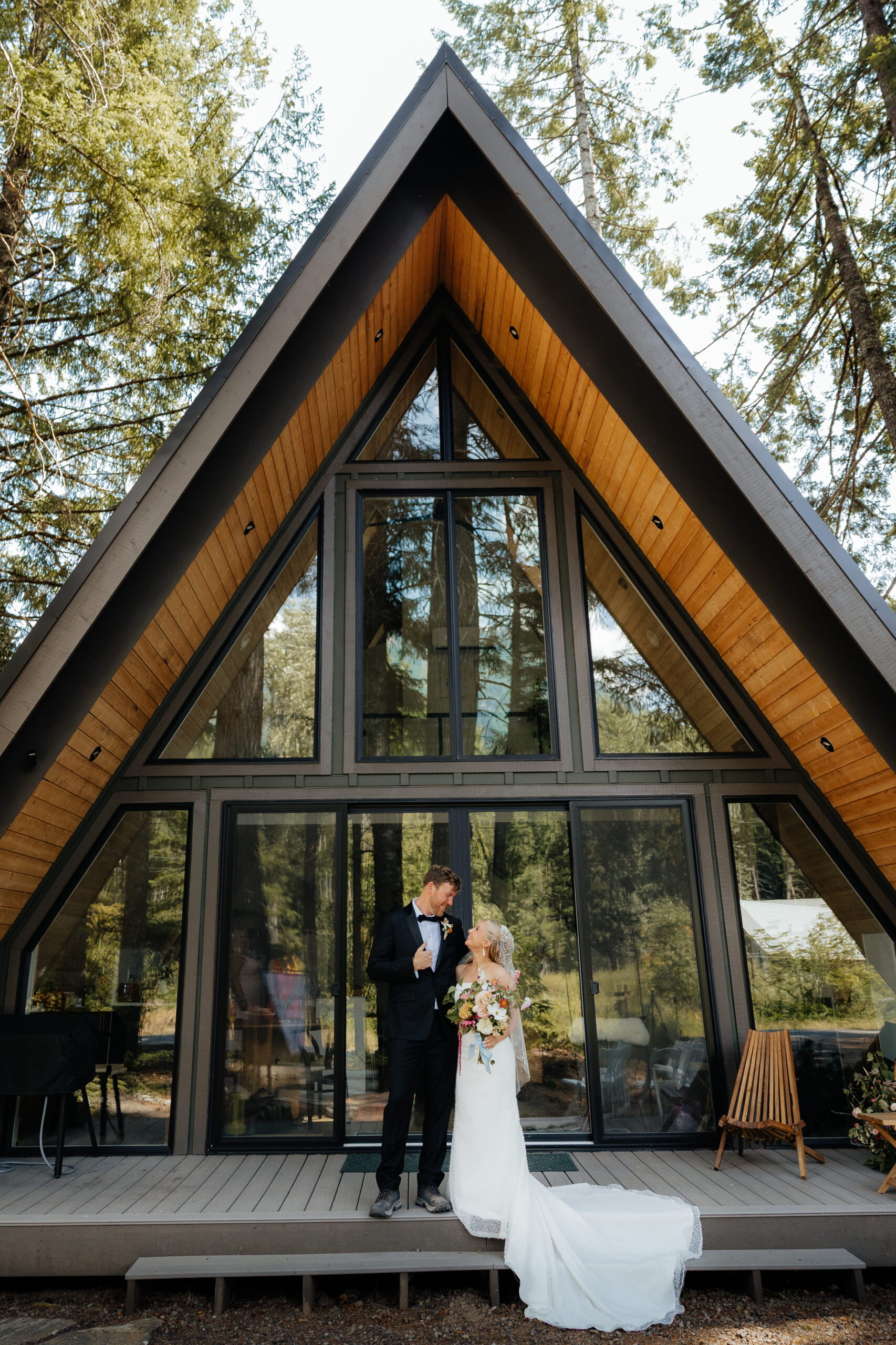 Newlyweds stand on the porch of an a-frame cabin near Mt Rainier National Park.
