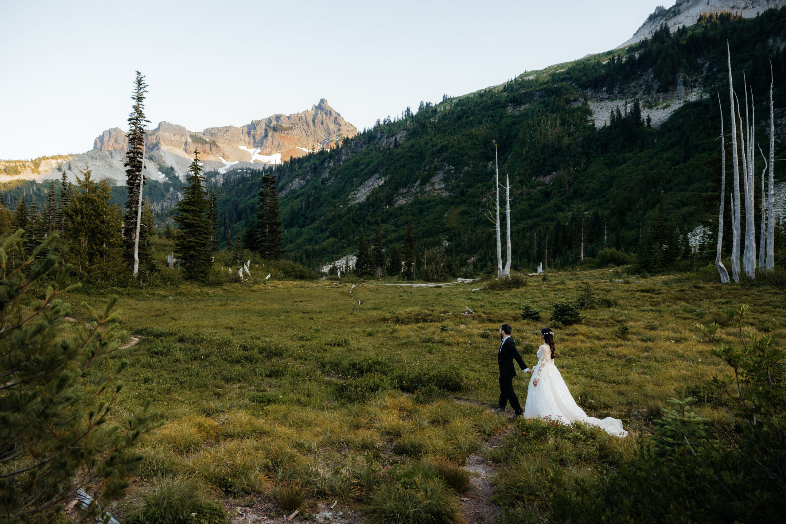 Newlyweds hold hands while hiking at Mt. Rainier during their summer elopement.