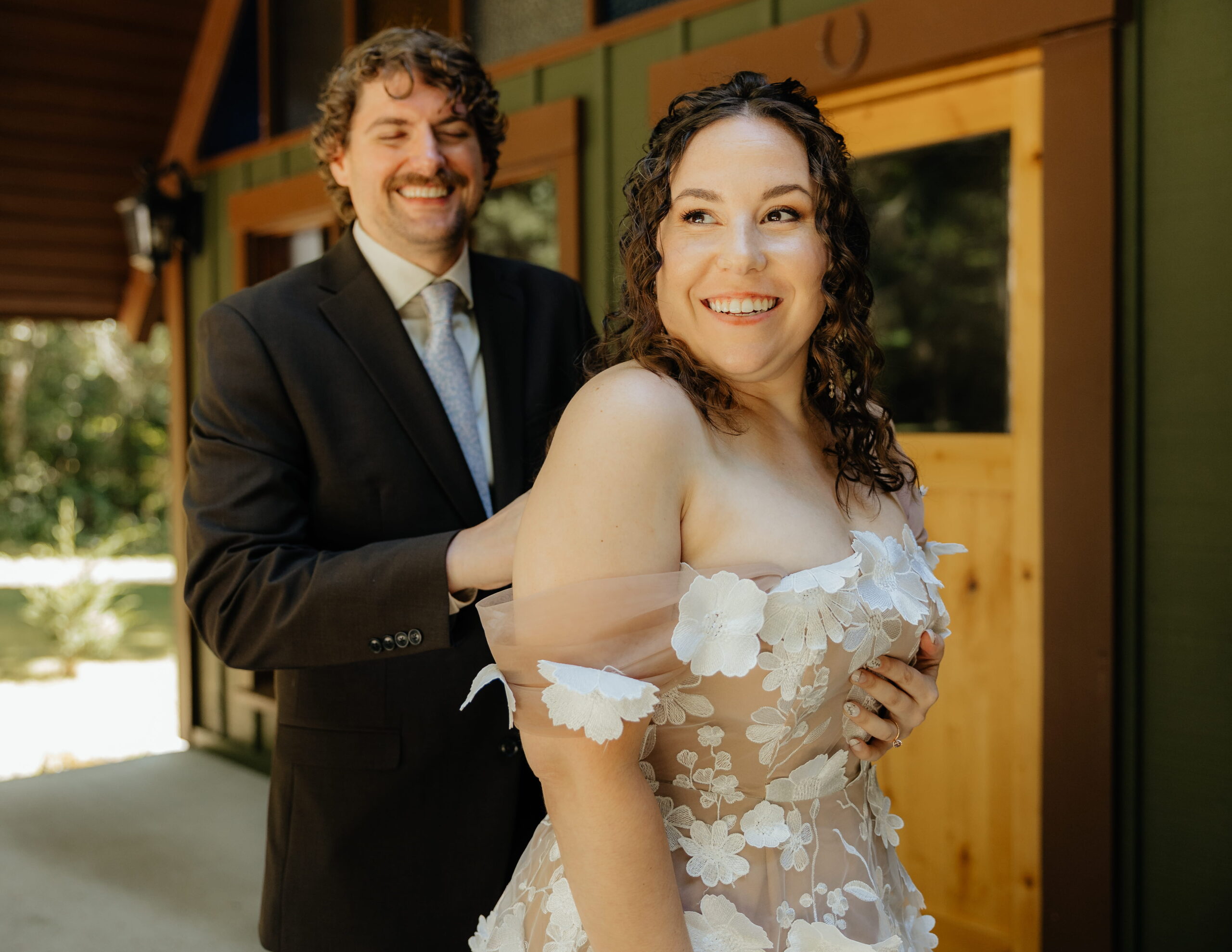Groom helps bride zip into her wedding dress during getting ready at their Mt Rainier A-frame cabin. 