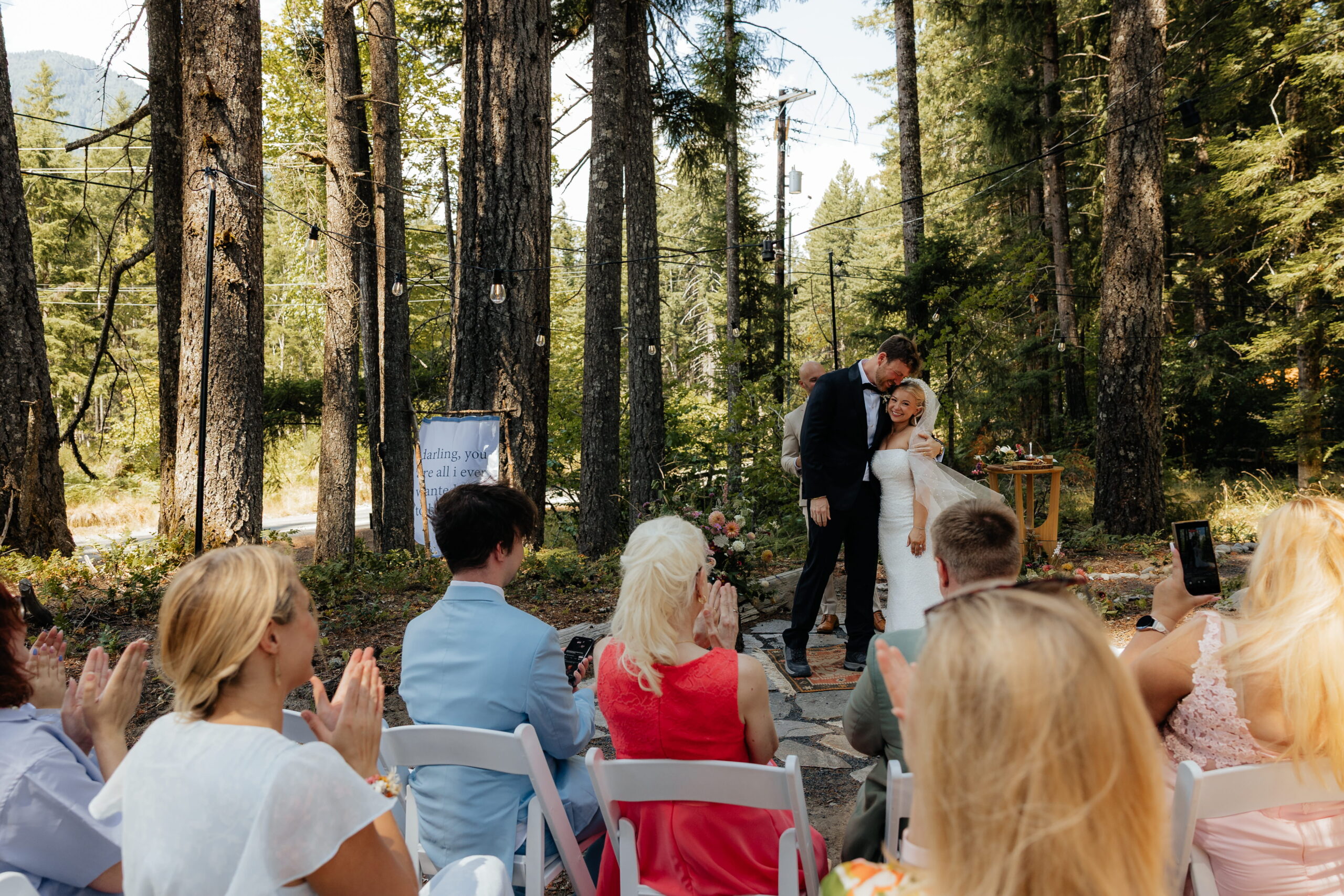 Newlyweds side hug while family claps after their elopement wedding ceremony near Mt Rainier.