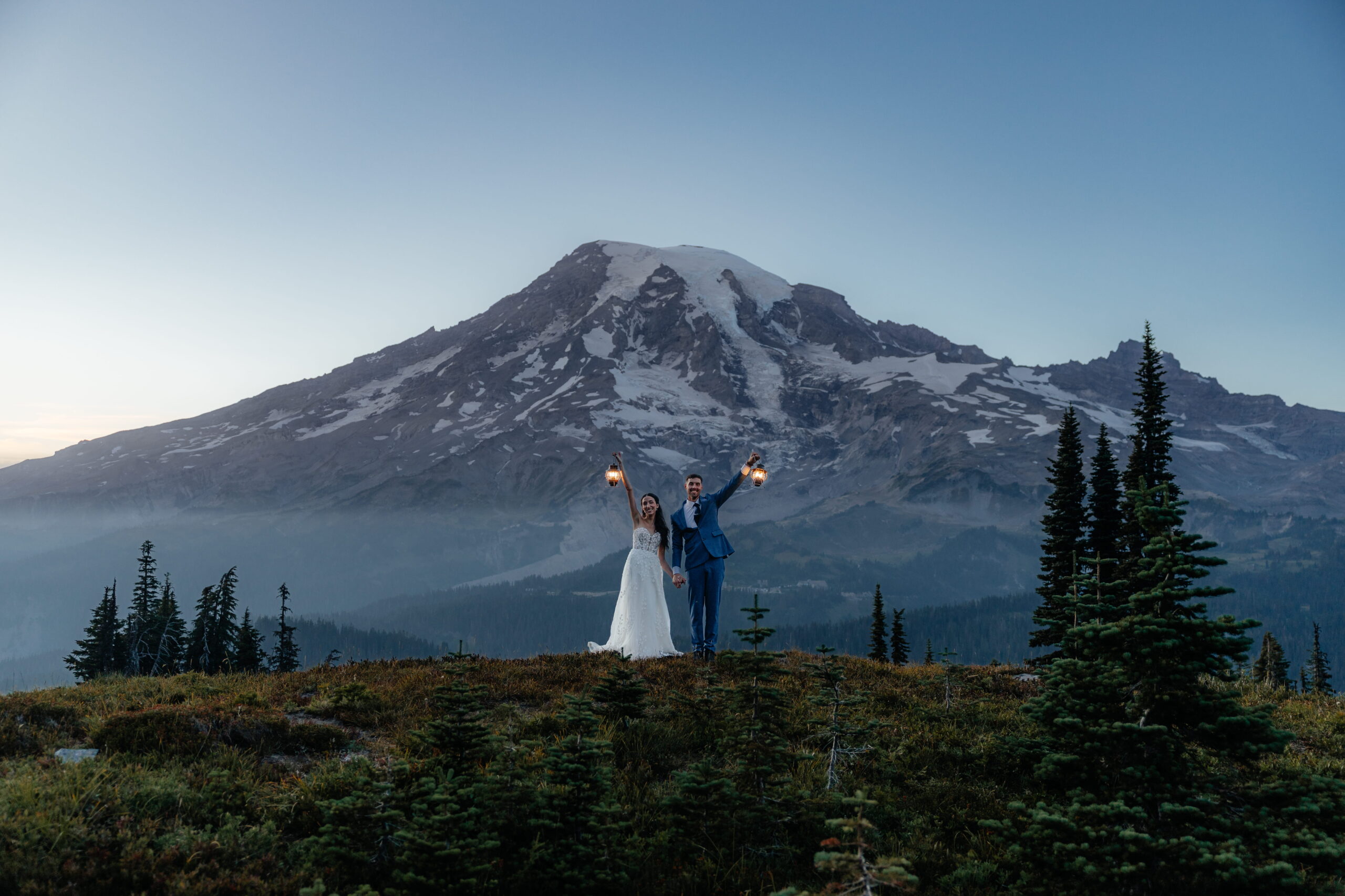 Newlyweds hold lanterns in front of Mt Rainier during their full-day elopement.