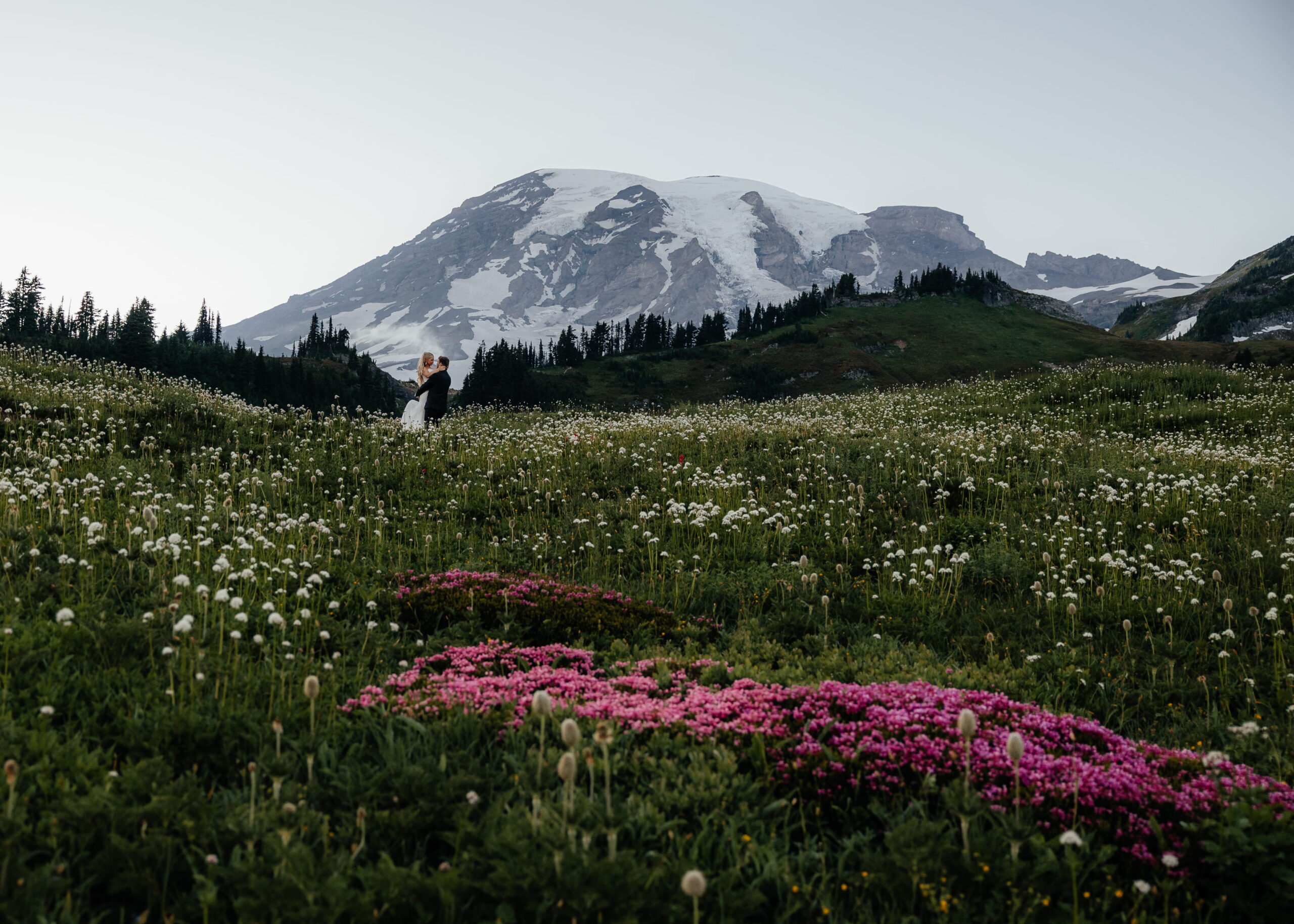 Newlyweds dance in a wildflower field during their elopement at Mt. Rainier.