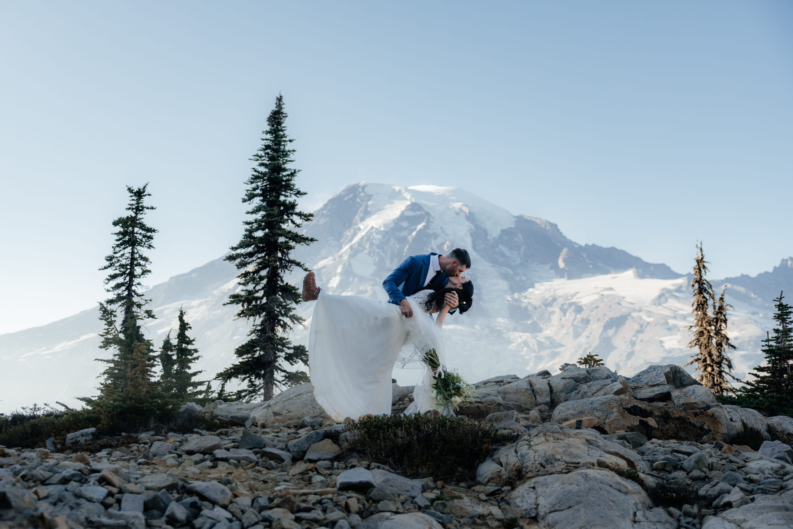 Newlyweds go for a dip kiss on a mountain trail during their Mt Rainier elopement.