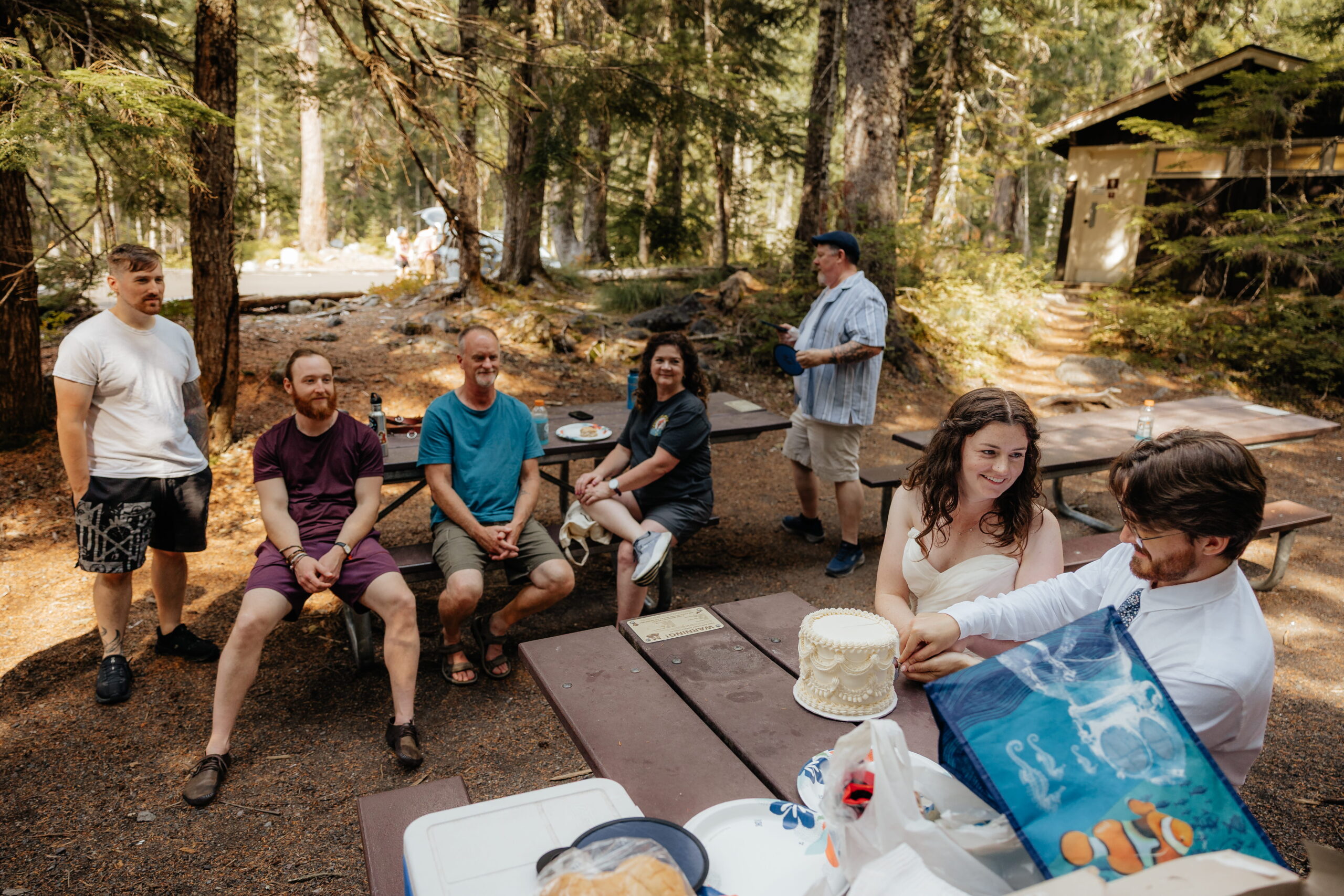 Newlyweds cut cake on a picnic table at Mt. Rainier National Park.